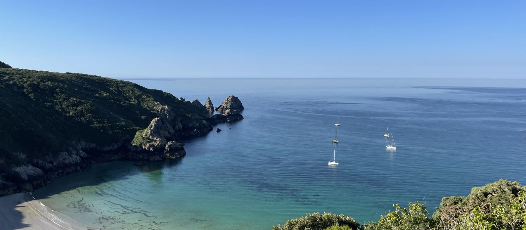A quiet bay on Guernsey’s south coast, with yachts at anchor and cliffs falling to clear water